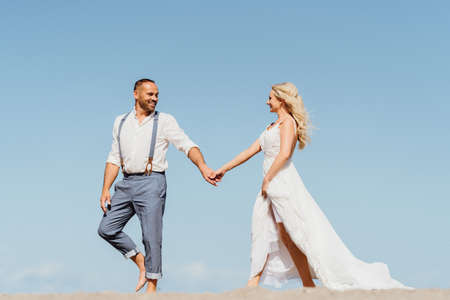 happy pretty newly married couple walking on the beach. Wedding on the beachの写真素材