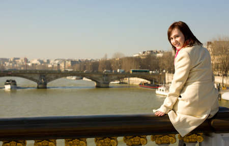 Happy beautiful girl in Paris sitting on the balustrade of Pont Alexandre IIIの写真素材