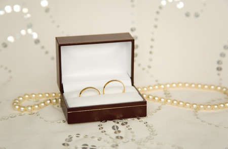 Two golden wedding rings with pearl necklace and bridal veil