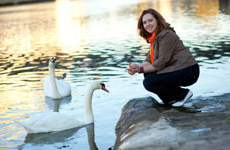 Happy beautiful girl in Paris feeding swansの写真素材