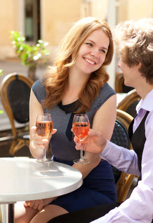Beautiful couple having a date in a cafe and drinking rose wineの写真素材