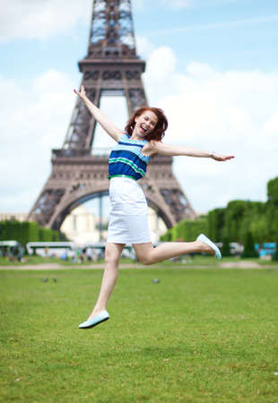 Happy beautiful girl jumping near the Eiffel Tower in Parisの写真素材
