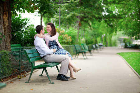 Happy dating couple hugging on a bench in a Parisian parkの写真素材