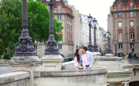 Dating couple is kissing tenderly in Paris on a bridgeの写真素材
