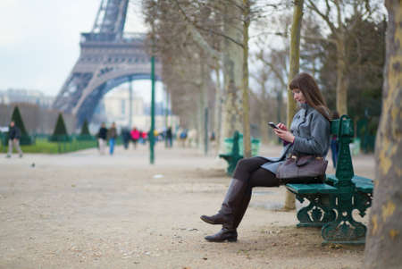 Girl sending sms or surfing in the net in Parisの写真素材
