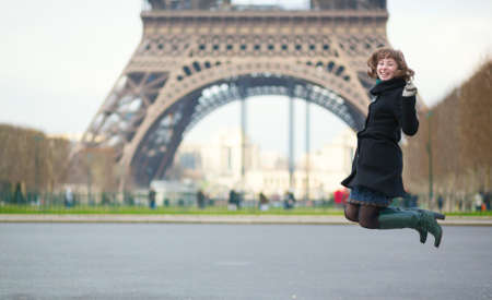Happy young girl jumping in front of the Eiffel towerの写真素材