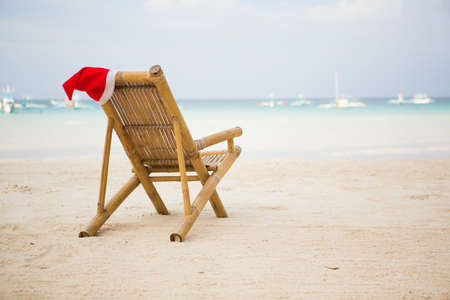 Santa hat on chaise longue on white sand beachの写真素材