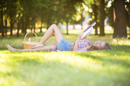 Beautiful young girl reading a book in parkの写真素材