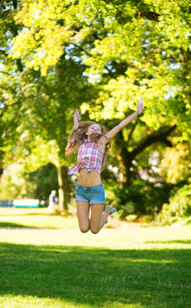 Happy girl jumping in parkの写真素材