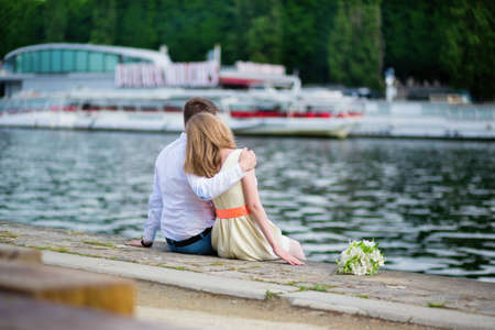 Young newly-wed couple sitting on the Seine embankment in Parisの写真素材