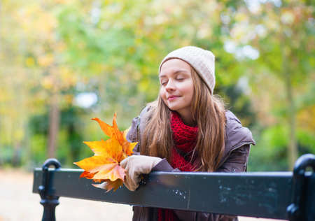Sad girl sitting on a bench in park alone