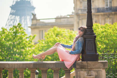 Beautiful girl in pink dress sitting near the Eiffel tower in Parisの写真素材