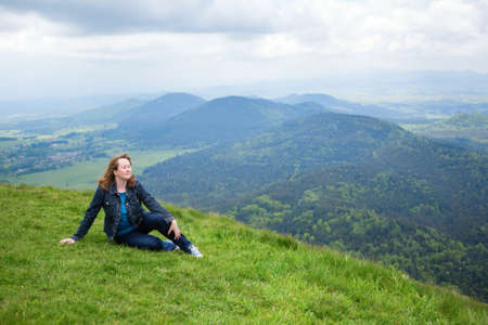 Relaxed girl sitting on the slope of volcano in Auvergne, Franceの写真素材