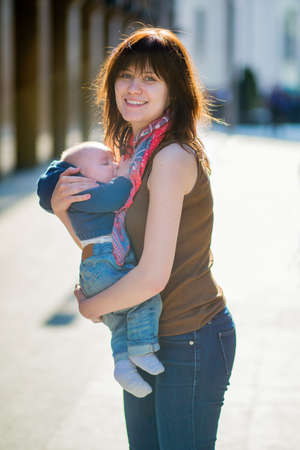 Happy young mother with her little baby boy outdoors
