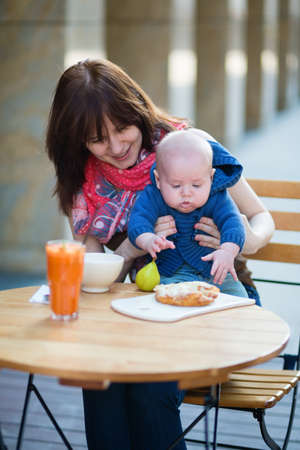 Happy young mother with her 4-month baby boy in an outdoor cafeの写真素材