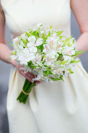 Young bride holding in her hands beautiful wedding flowersの写真素材