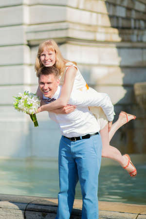 Happy just married couple on Montmarte, man is piggybacking womanの写真素材