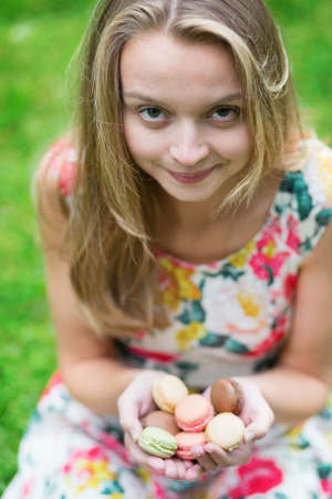 Beautiful young girl holding traditional French macaroons in handsの写真素材