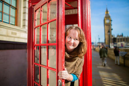 Happy young tourist in London looking out of the red phonebox, Big Ben in the backgroundの写真素材
