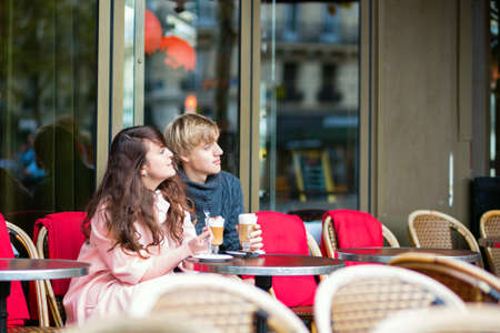 Young dating couple drinking coffee in a Parisian outdoor cafeの写真素材