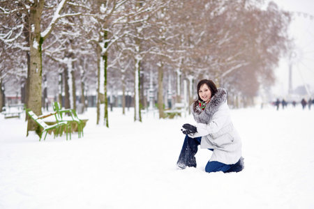 Beautiful young woman in the Tuileries garden enjoying rare snowy winter day in Parisの写真素材