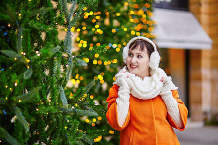 Cheerful young woman in Paris on a winter day, enjoying Christmas season