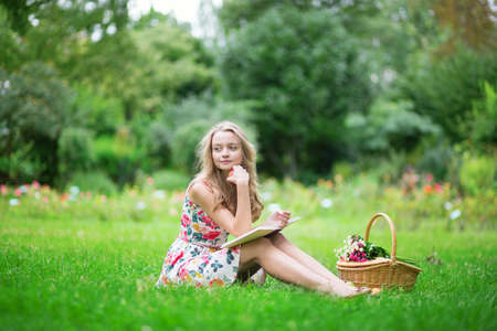 Beautiful young girl in the countryside, reading a bookの写真素材