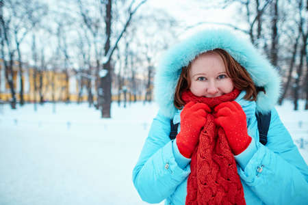 Smiling girl in red scarf walking in park on a cold winter day