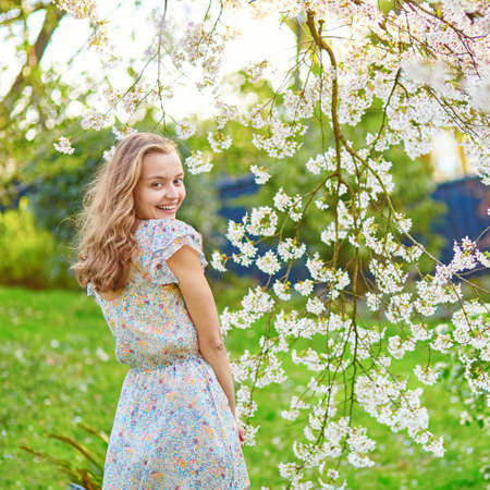 Beautiful young woman in cherry blossom garden on a spring dayの写真素材