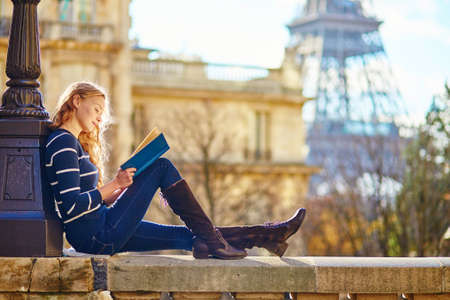 Beautiful young woman in Paris, reading a bookの写真素材