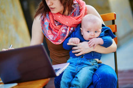 Young working mother with her little son in a cafeの写真素材