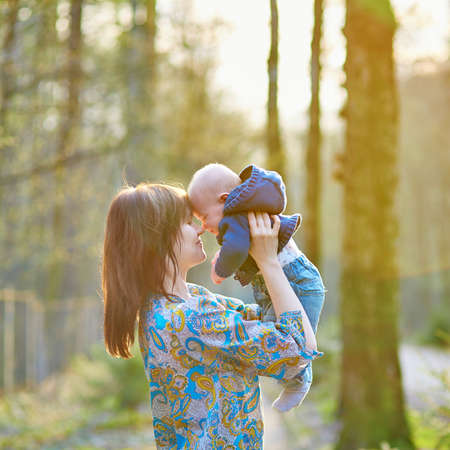 Young mother with her adorable little baby in forest on a spring dayの写真素材