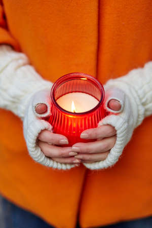 Woman holding burning candle in her handsの写真素材