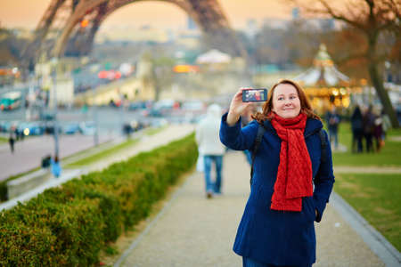 Happy young woman taking a selfie with mobile phone in Paris, France
