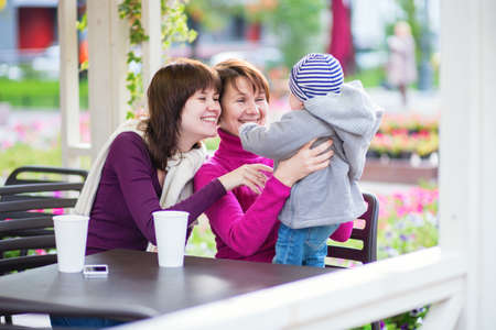Three generations family - grandmother, mother and little son spending time together in an outdoor...