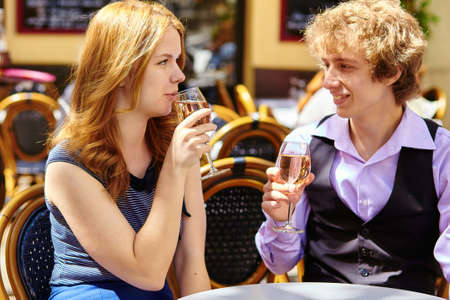 Beautiful couple having a date in a Parisian cafe and drinking rose wineの写真素材