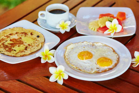 Traditional Balinese breakfast with fried eggs, pineapple pancake and fresh fruitsの写真素材