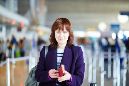 Beautiful young female passenger at check-in counter in the airportの写真素材
