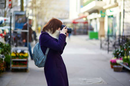 Beautiful young tourist in Paris, taking a photo on the streetの写真素材