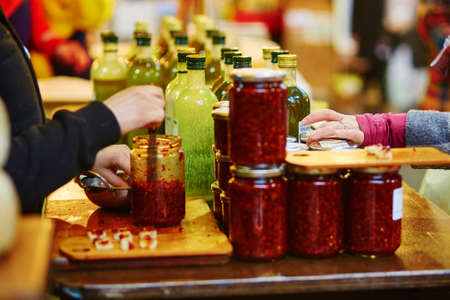 Woman degusting fresh organic extra virgin olive oil and different sauces on farmer agricultural marketの写真素材