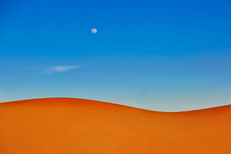 Sand dunes and almost full moon in the Sahara Desert, Merzouga, Moroccoの写真素材