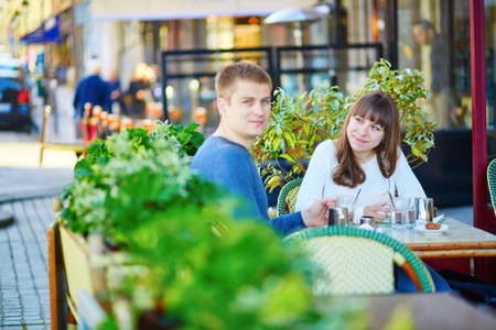 Young romantic couple having a date in a Parisian outdoor cafe, drinking hot chocolateの写真素材