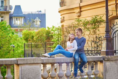 Beautiful romantic couple in Paris sitting outdoors together and huggingの写真素材
