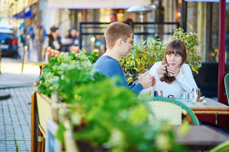 Young romantic couple having a date in a Parisian outdoor cafe, drinking hot chocolateの写真素材