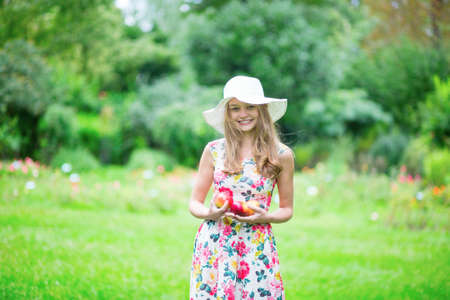 Beautiful young girl in white hat holding applesの写真素材