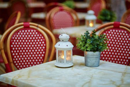 Table in cozy outdoor cafe with a small lantern and plant decoration on itの写真素材
