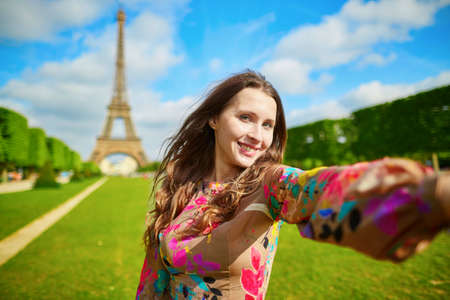 Woman tourist at Eiffel Tower smiling and making travel selfie. Beautiful European girl enjoying...