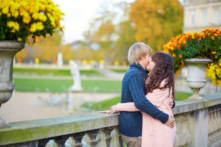 Young dating couple in the Luxembourg gardens of Paris on a bright fall day, kissingの写真素材