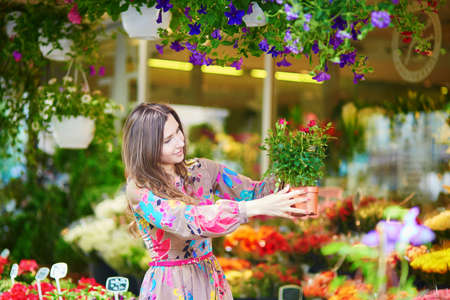 Beautiful young customer selecting fresh flowers in Parisian flower shop or on marketの写真素材