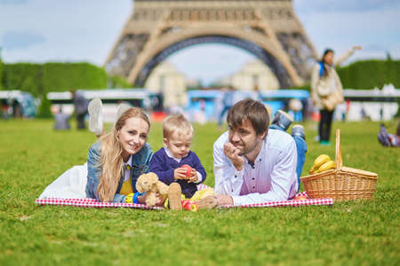 Happy family of three, mother, father and little toddler boy, having picnic in Paris near the Eiffel towerの写真素材
